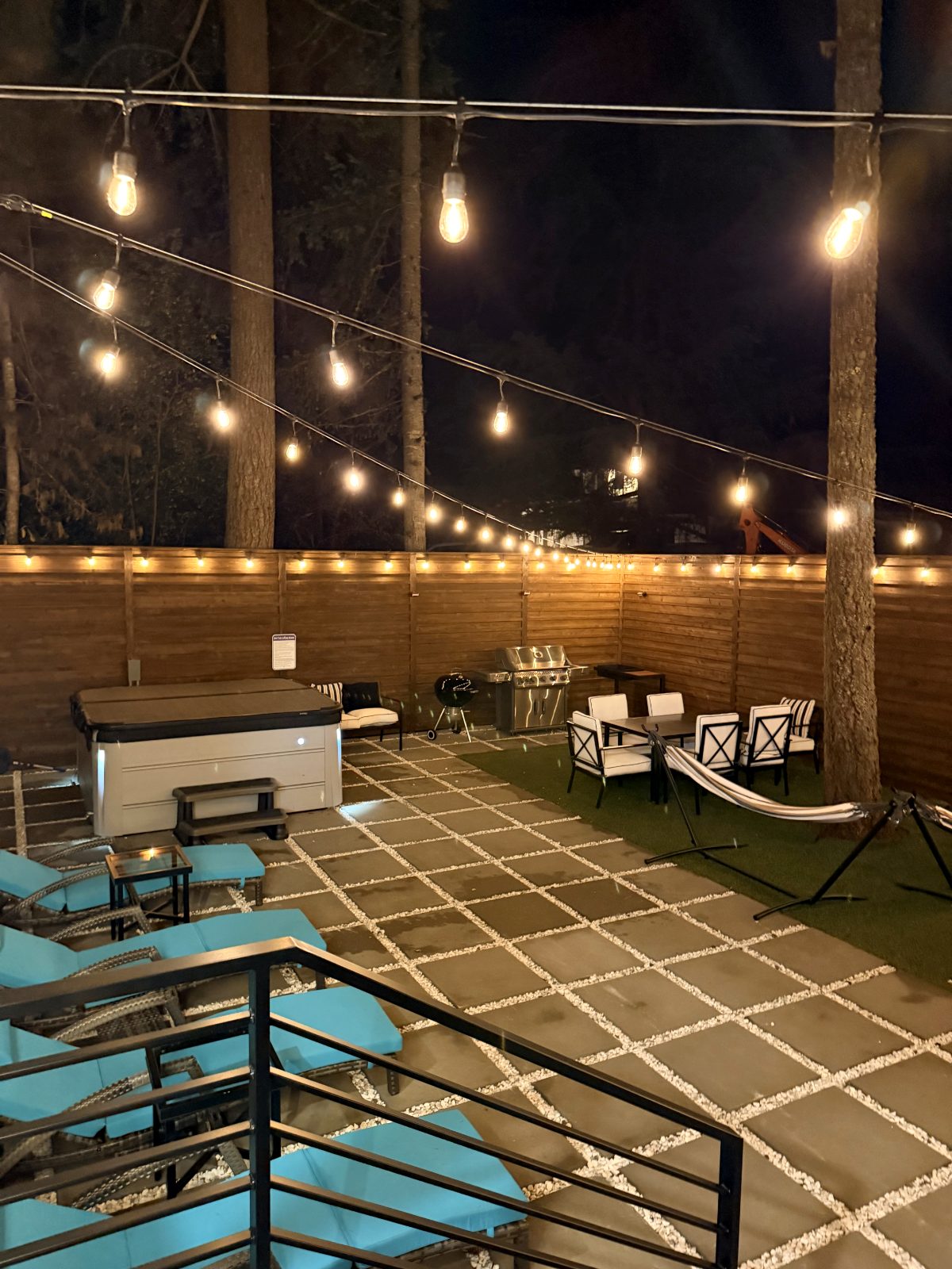 Hot tub, lounge chairs and BBQ in the backyard at night
