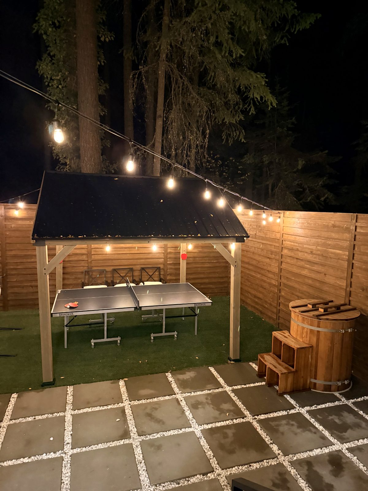 Cedar cold plunge barrel next to a gazebo under string lights
