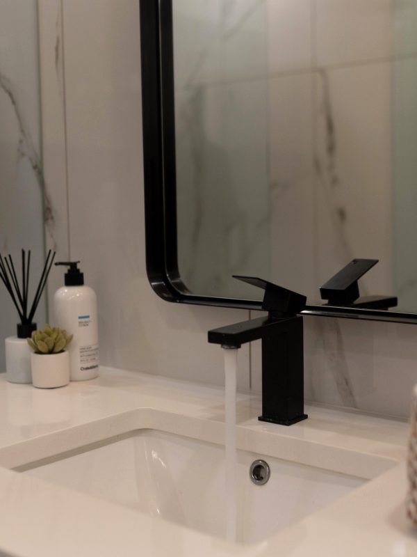 Vanity with a black faucet and a mirror