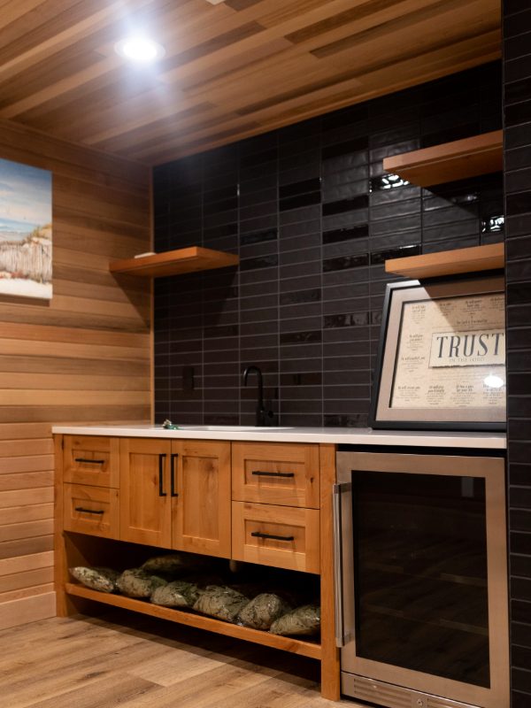 Wooden bar with a wine fridge and black tile wall