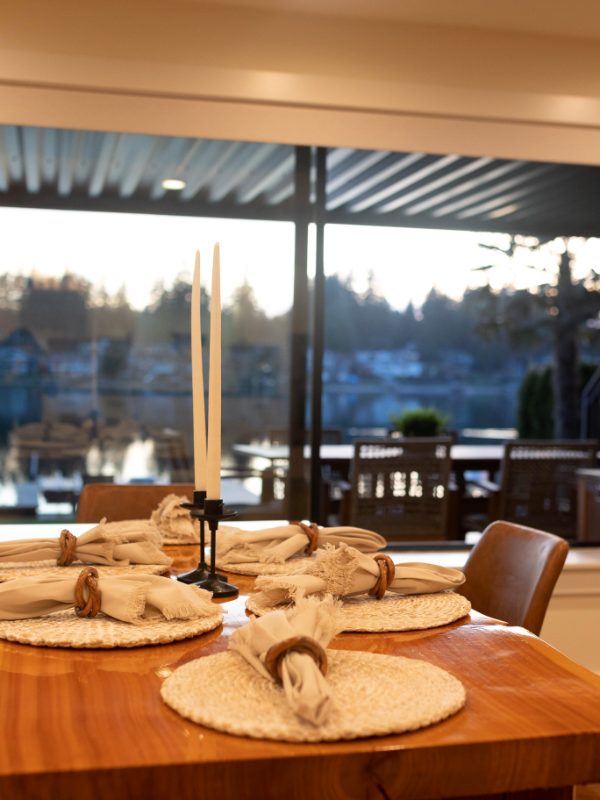 Dining table set for guests in front of a window to the lake