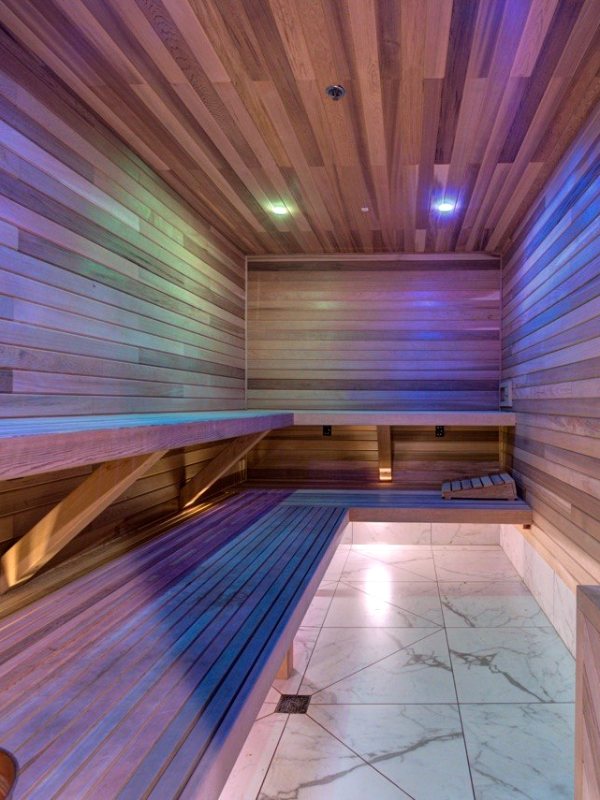 Cedar sauna with long benches, marble floor and a stone heater