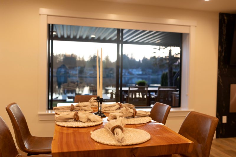 Dining table set for guests in front of a window to the lake