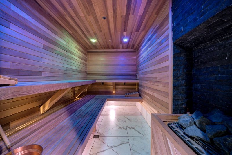 Cedar sauna with long benches, marble floor and a stone heater